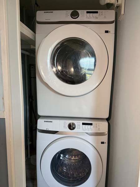 Stacked white washer and dryer in a narrow laundry closet