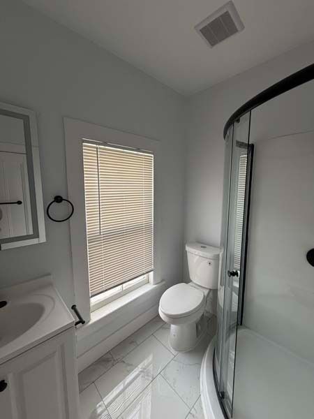 Bright white bathroom with toilet, tub, window blinds, and glass shower