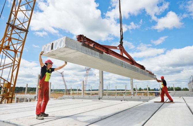 Construction workers lifting a concrete beam with a crane on a building site