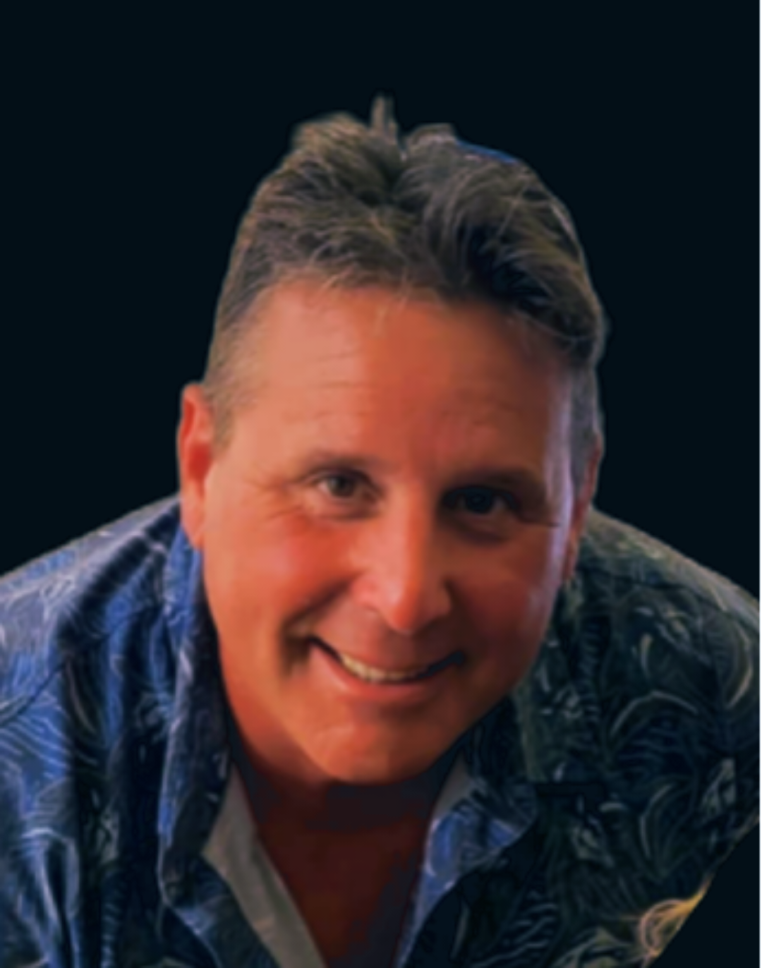 Smiling person in a blue patterned shirt against a dark background