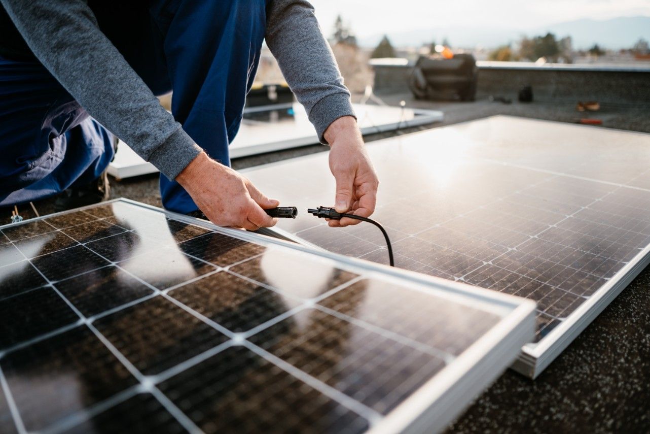 A Man is Installing Solar Panels on a Roof — Ravenshoe Auto Electrical In Ravenshoe, QLD
