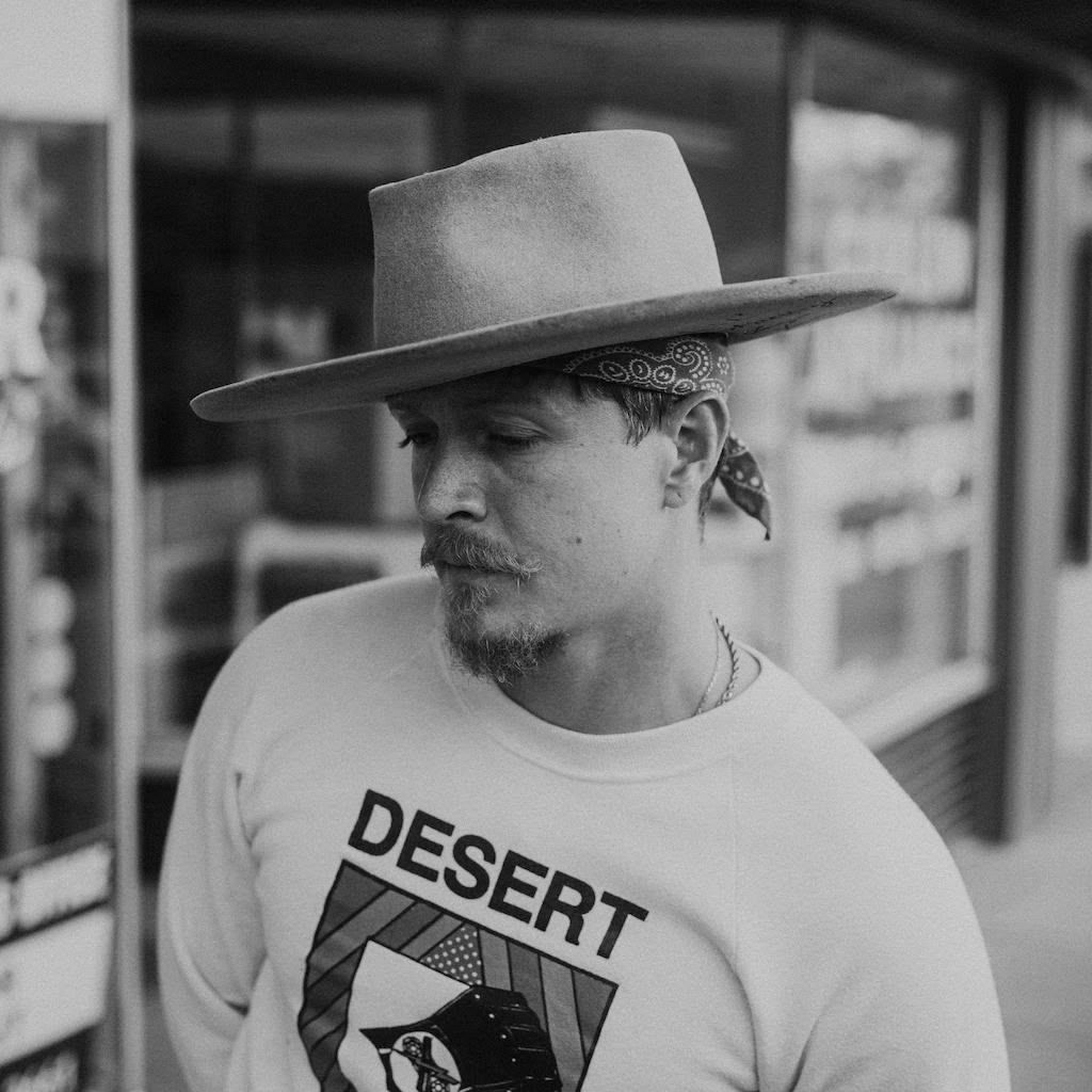 A black and white photo of a young man wearing a daytona hat
