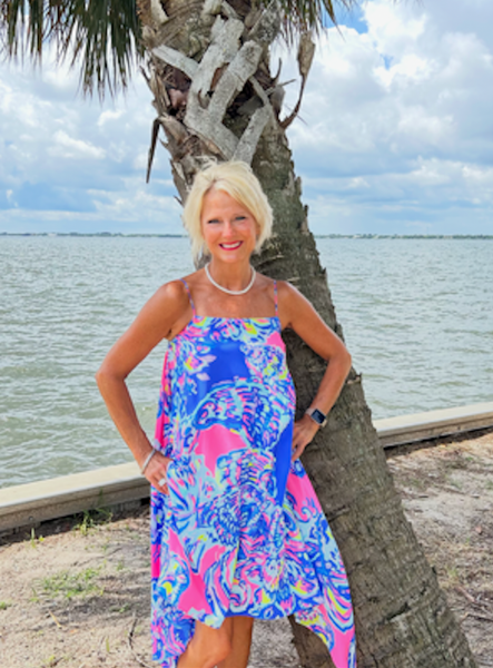 a woman in a pink jumpsuit stands in front of a wrought iron door