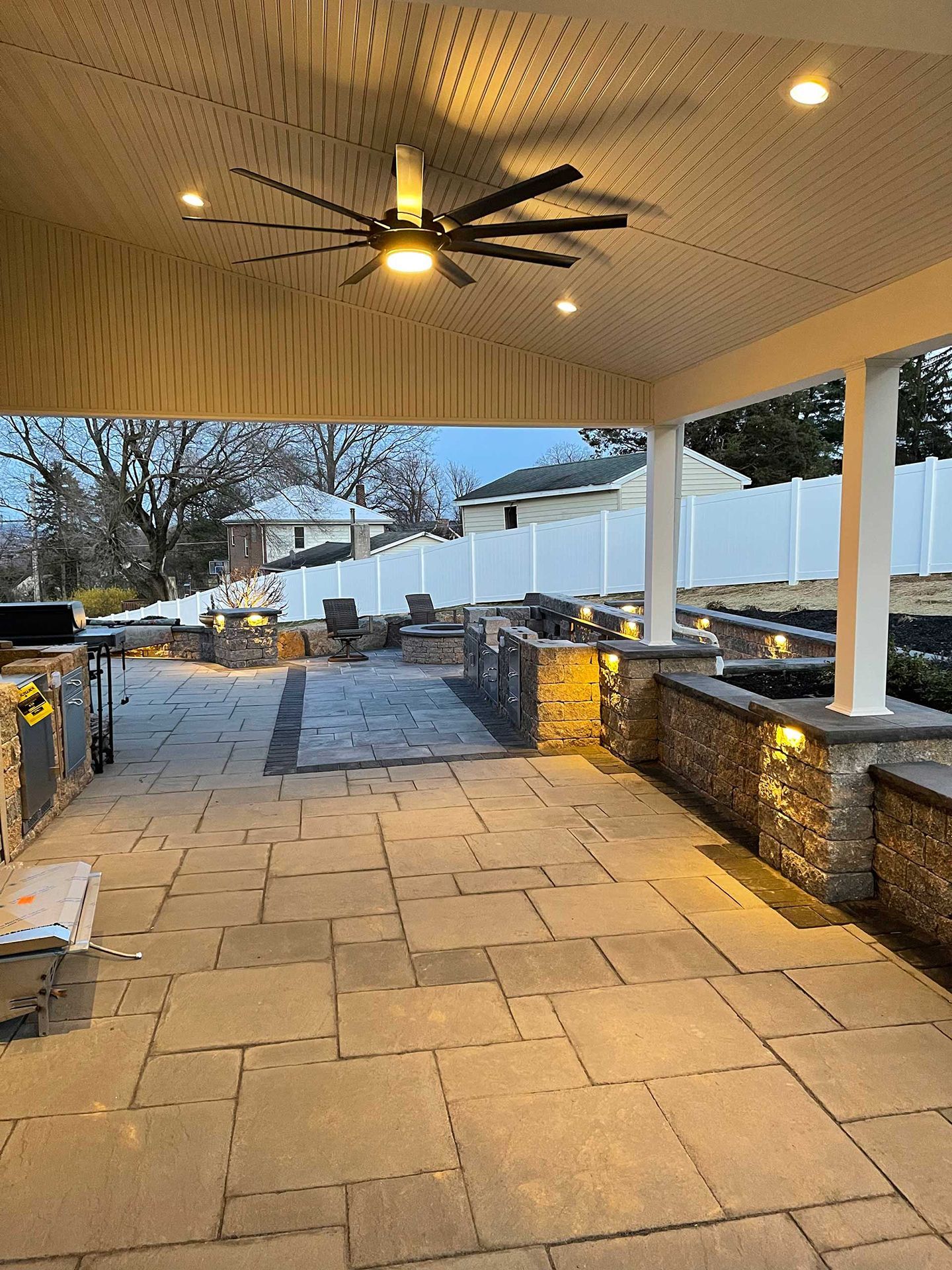 A large patio with a ceiling fan and a grill.