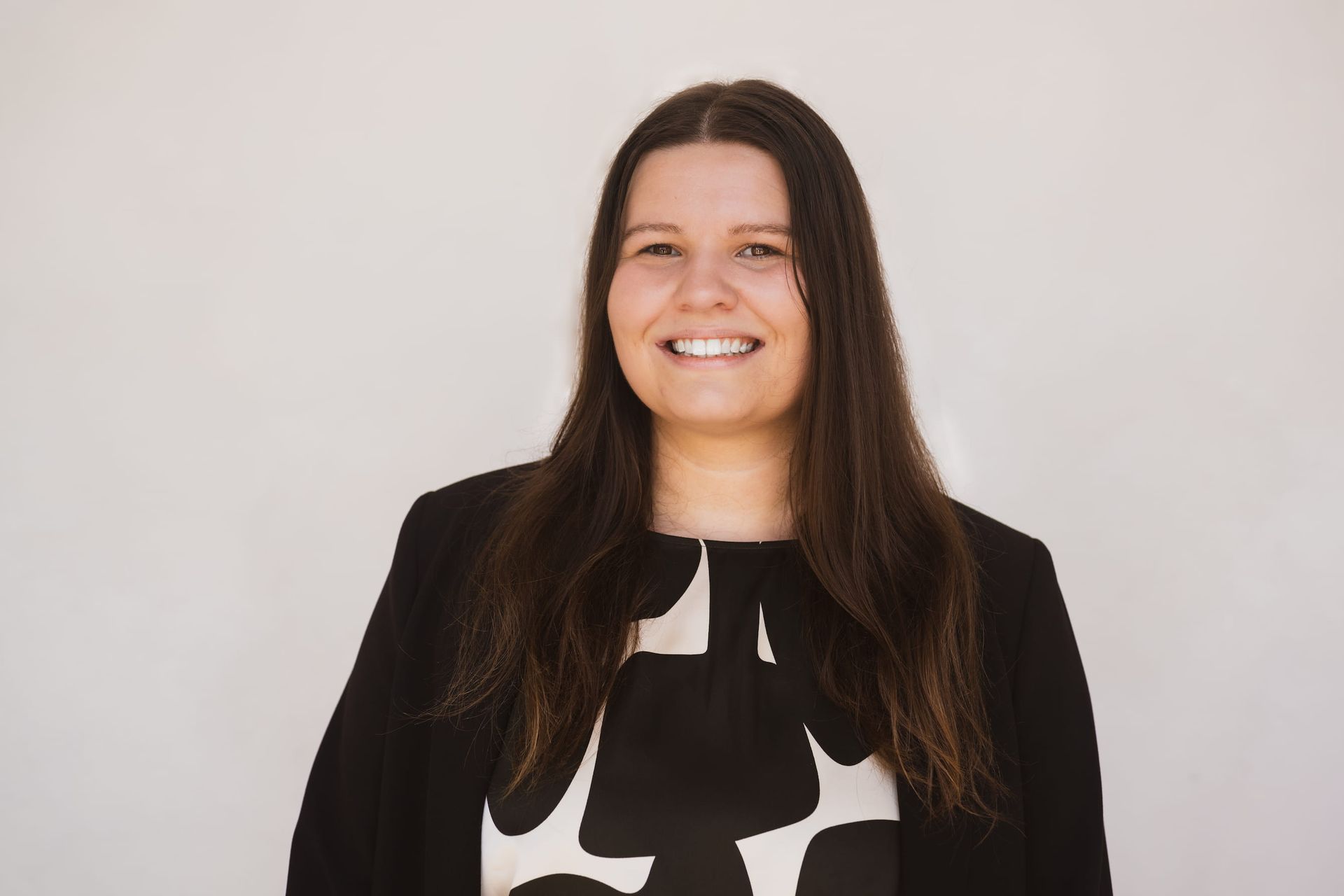 A woman in a black and white dress is smiling for the camera.