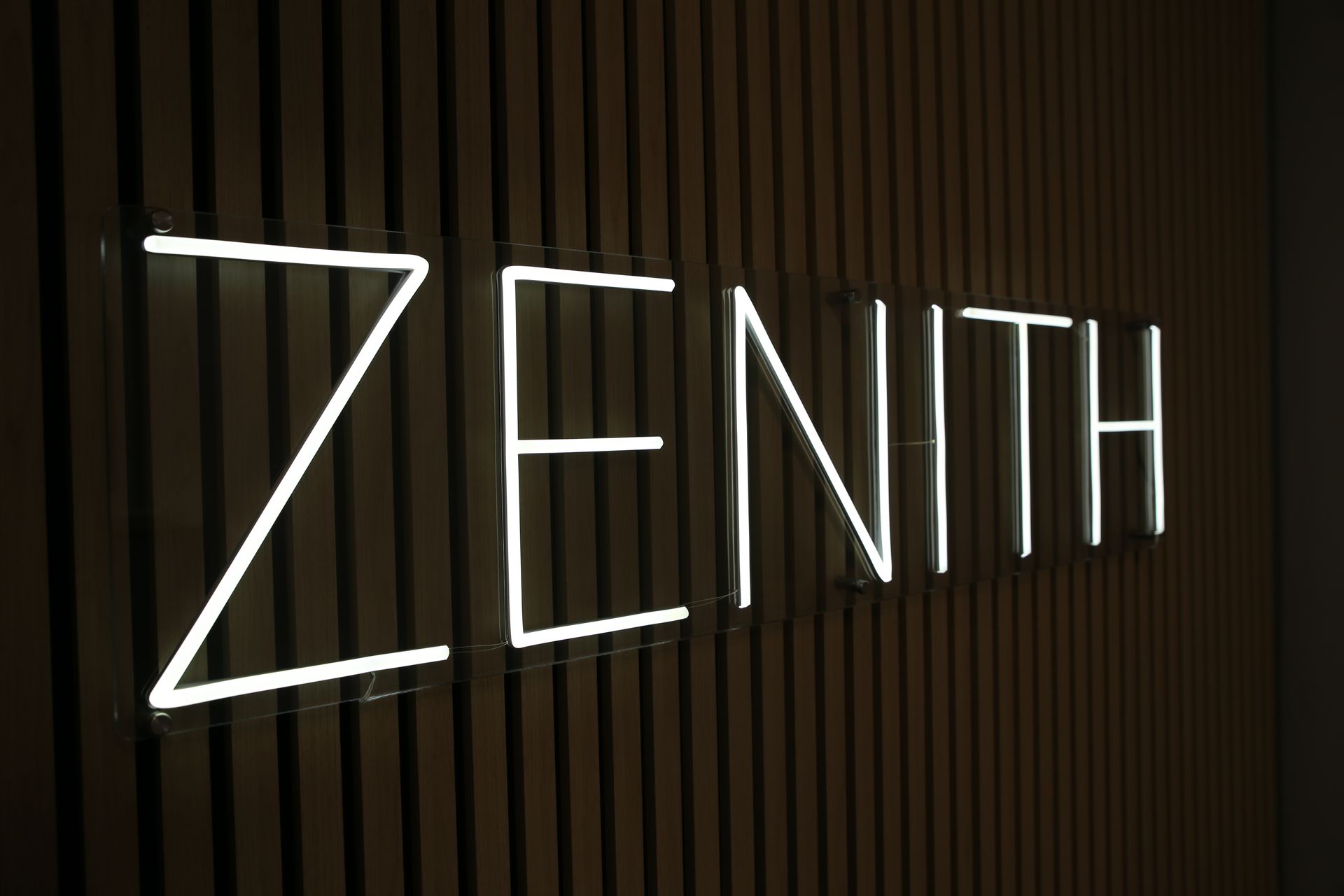 A neon sign that says zenith on a wall.