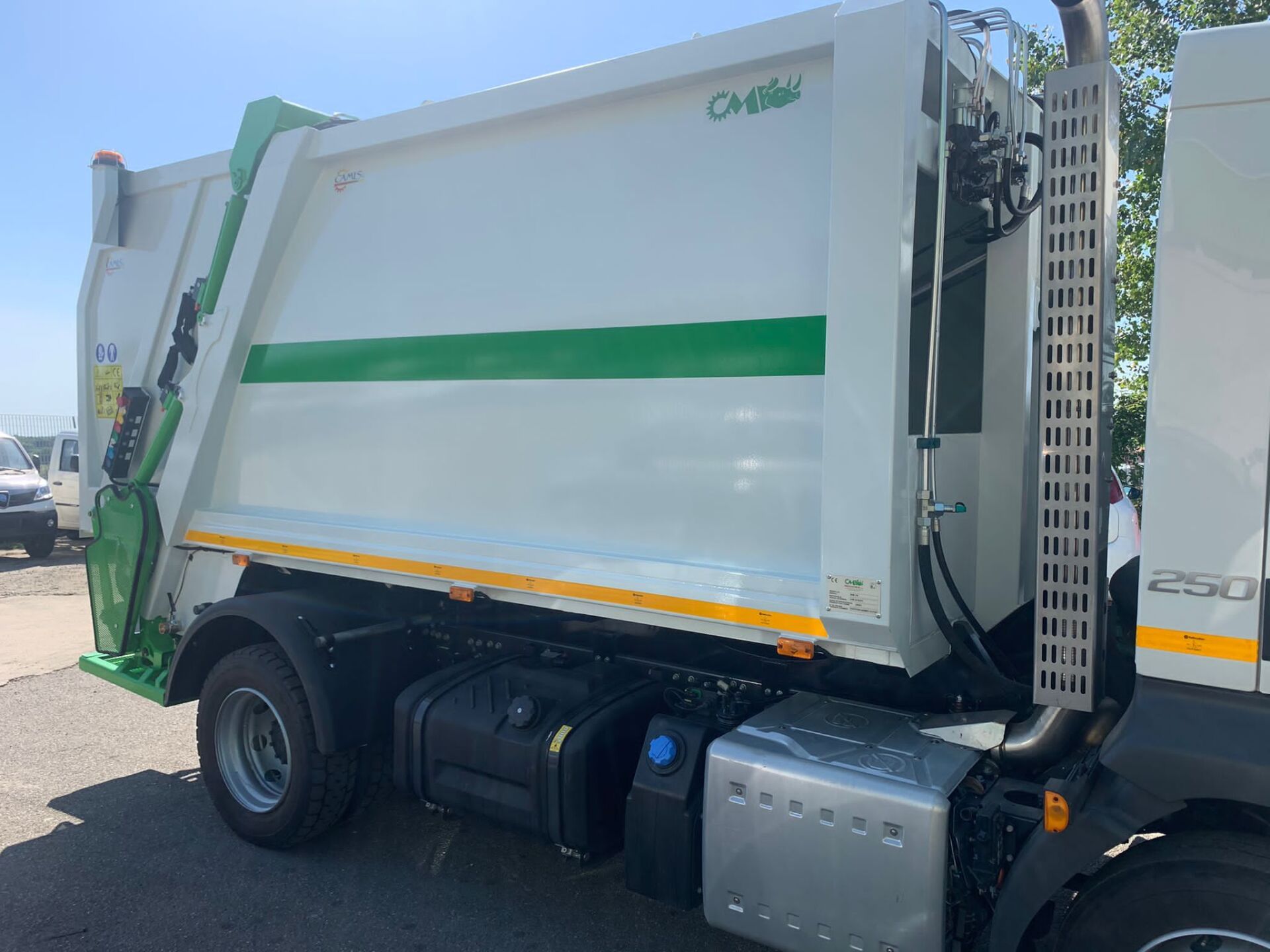 Camion della spazzatura bianco con striscia verde parcheggiato all'aperto in un parcheggio