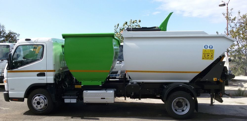 Autocarro ribaltabile bianco e verde con cassone rialzato, parcheggiato su una strada sotto un cielo azzurro.