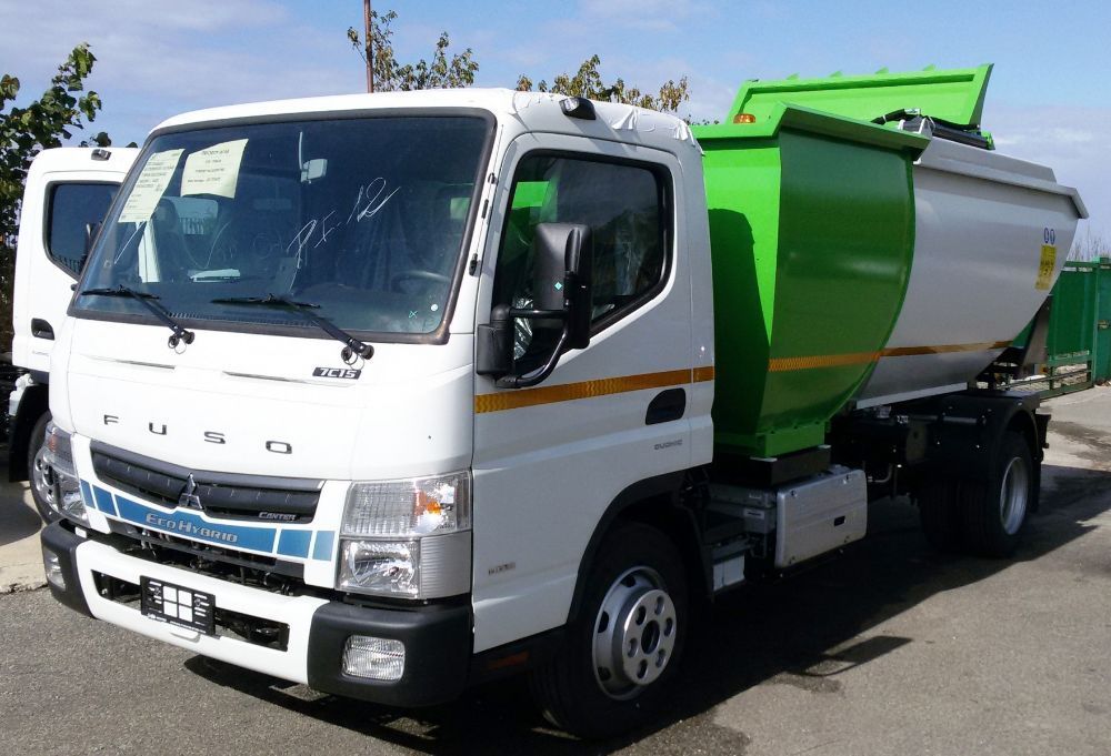 Camion della spazzatura bianco e verde parcheggiato all'aperto su una strada soleggiata