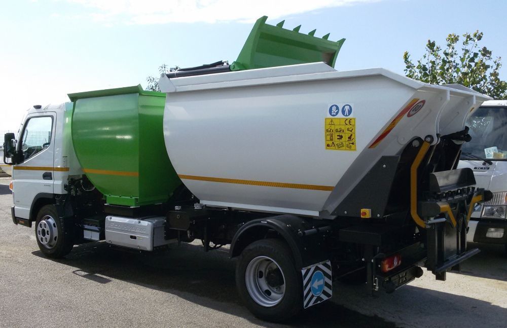 Camion della spazzatura bianco e verde parcheggiato all'aperto in una giornata di sole.