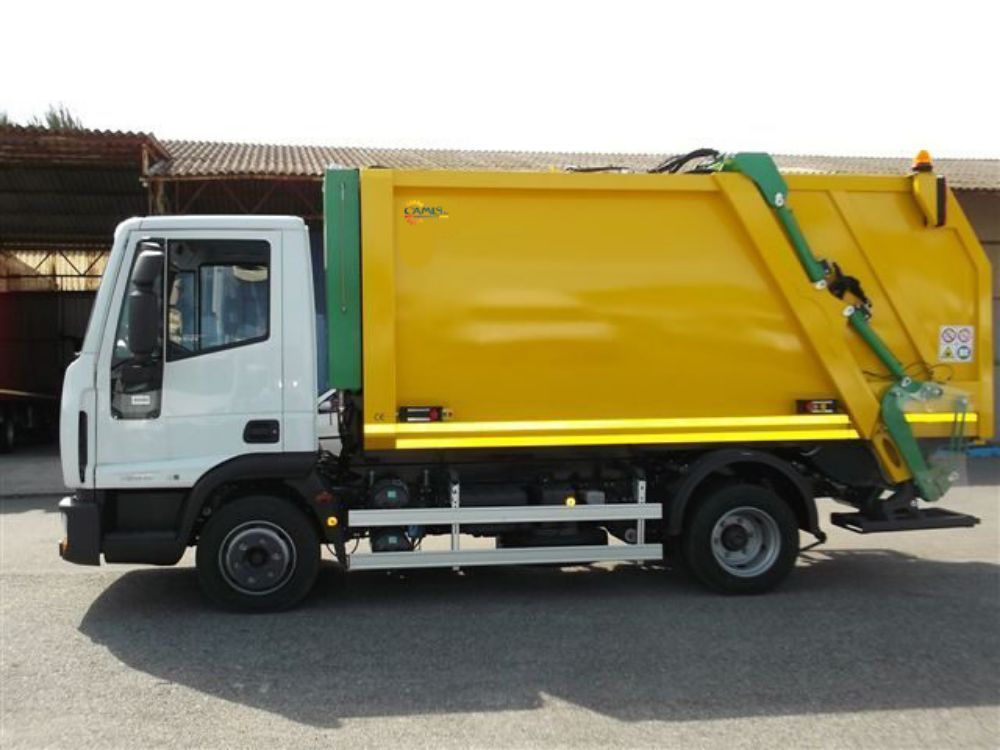 Camion della spazzatura giallo con cabina bianca parcheggiato all'aperto