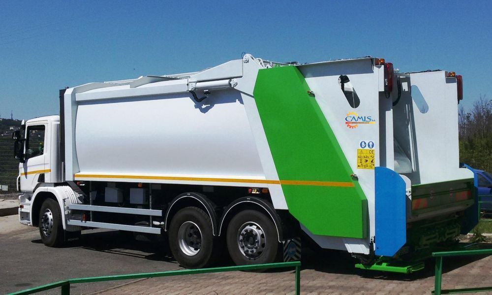 Camion della spazzatura bianco con segnaletica verde e blu parcheggiato all'aperto in un parcheggio