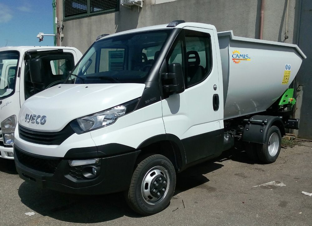 Autocarro ribaltabile Iveco bianco parcheggiato all'aperto in un piazzale, vista laterale.