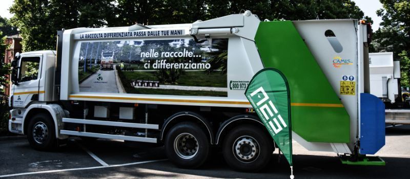 Vista laterale di un camion della spazzatura bianco e verde con il marchio 