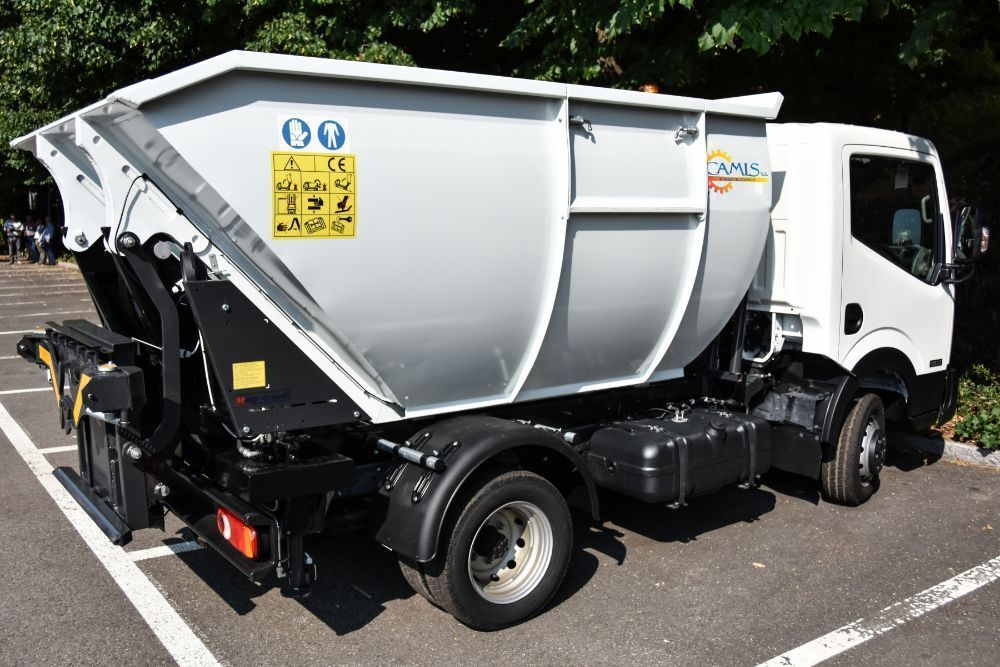 Camion della spazzatura bianco parcheggiato all'aperto su una strada soleggiata, vista laterale