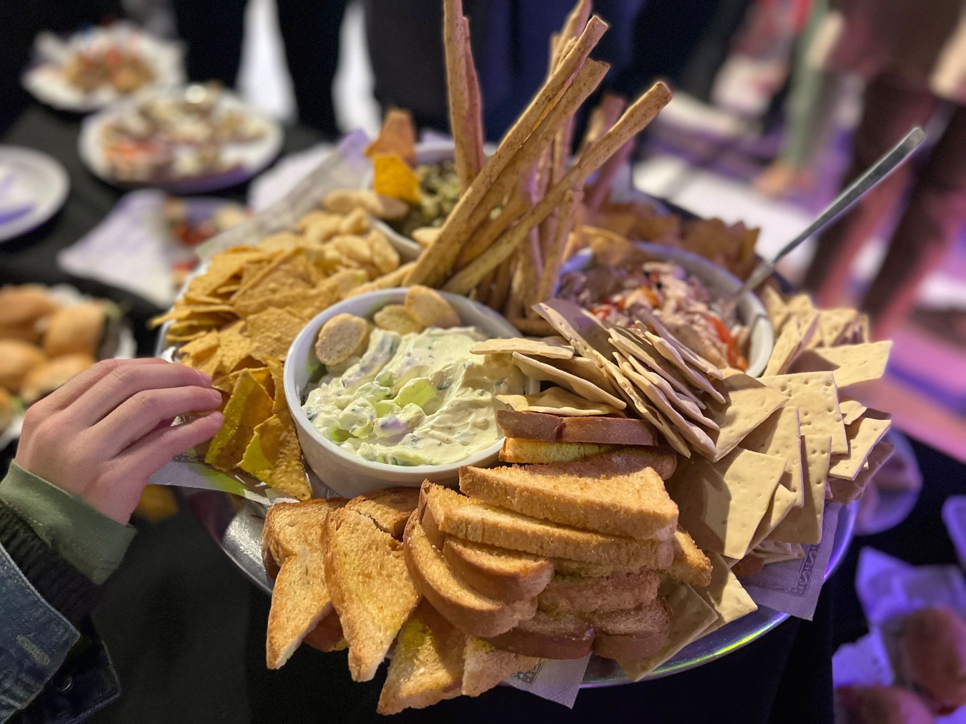 Gran bandeja de nachos variados y salsas para mojar sobre una mesa en una fiesta