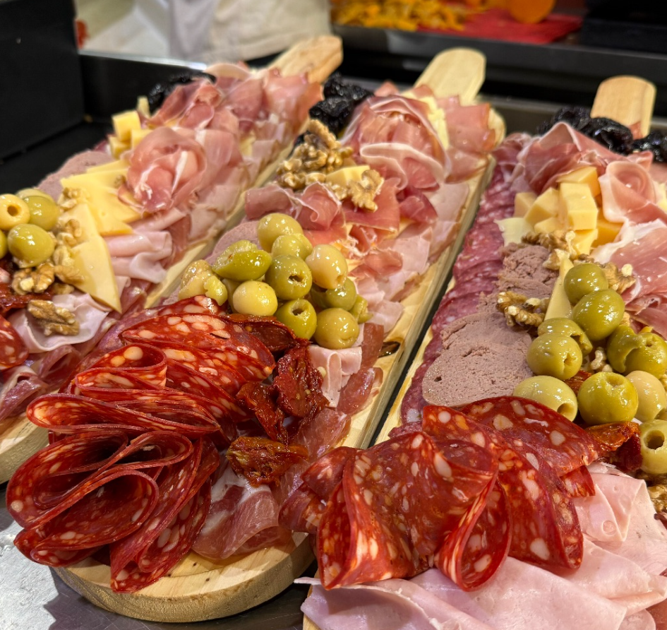 Tabla de embutidos con fiambres en lonchas, queso, aceitunas y pan en bandejas de madera