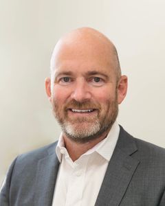 Dr. Jason Brady A bald man wearing scrubs and a stethoscope around his neck
