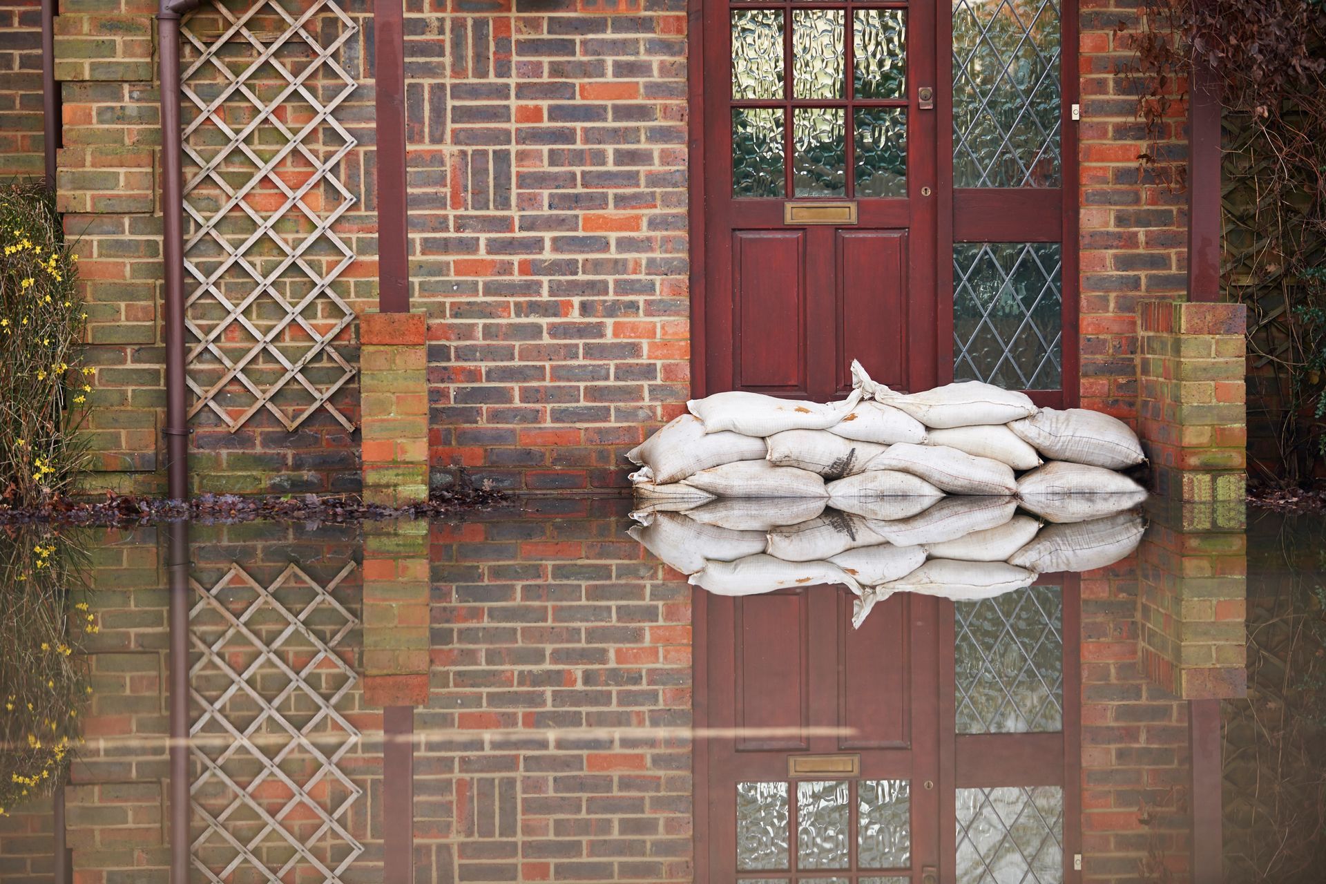 A flooded house with sandbags in front of it.