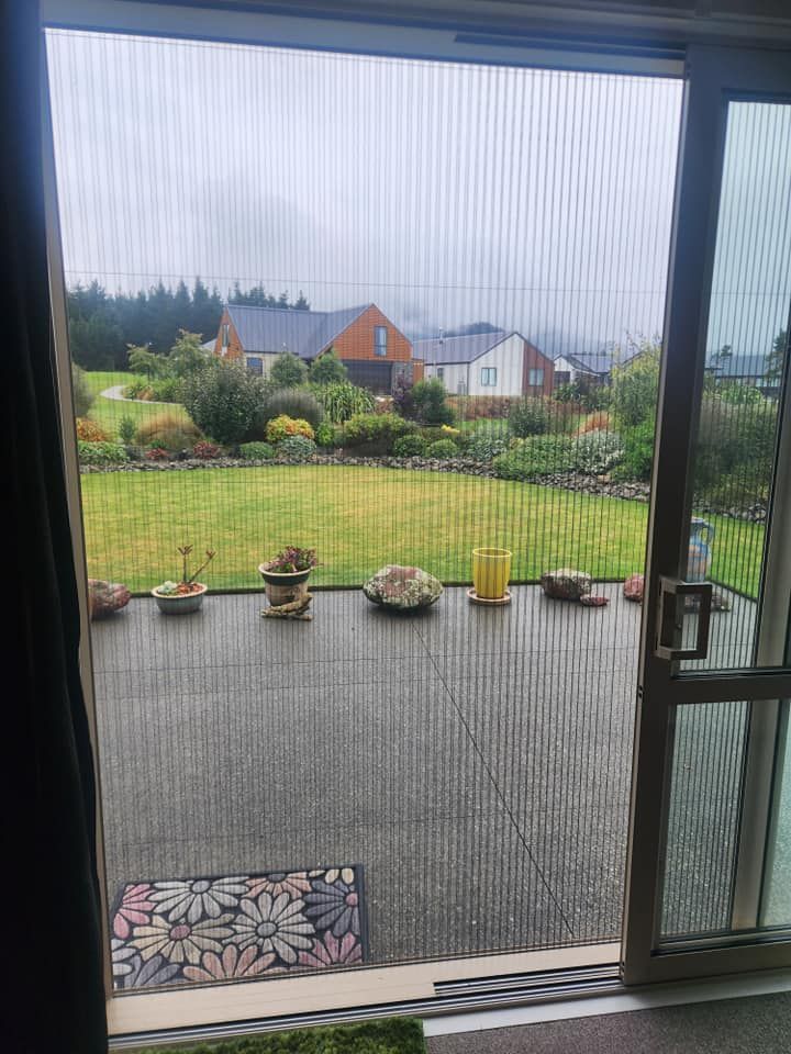 A view of a garden through a screen door.
