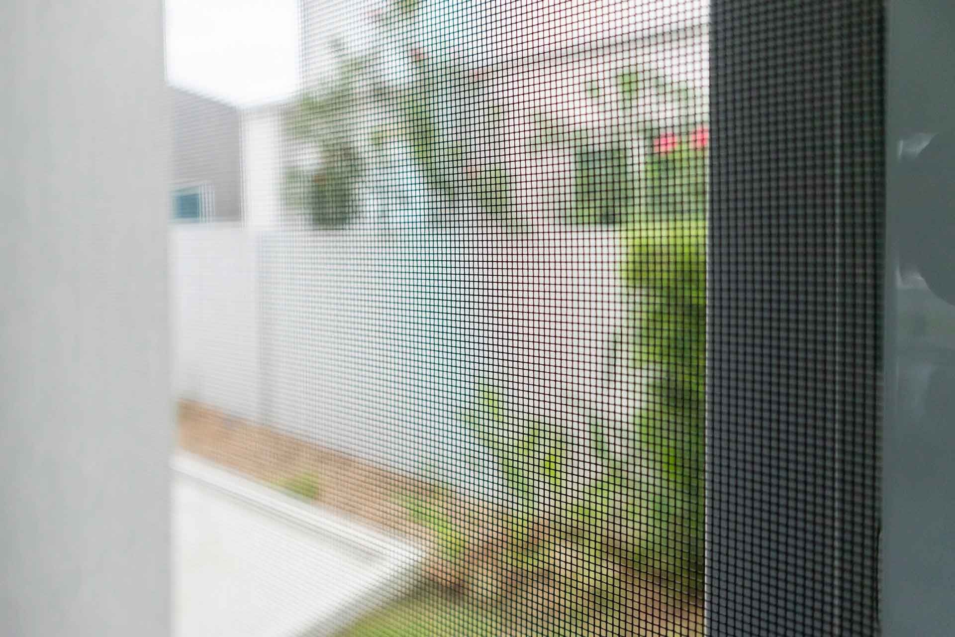 A close up of a mosquito screen on a window.