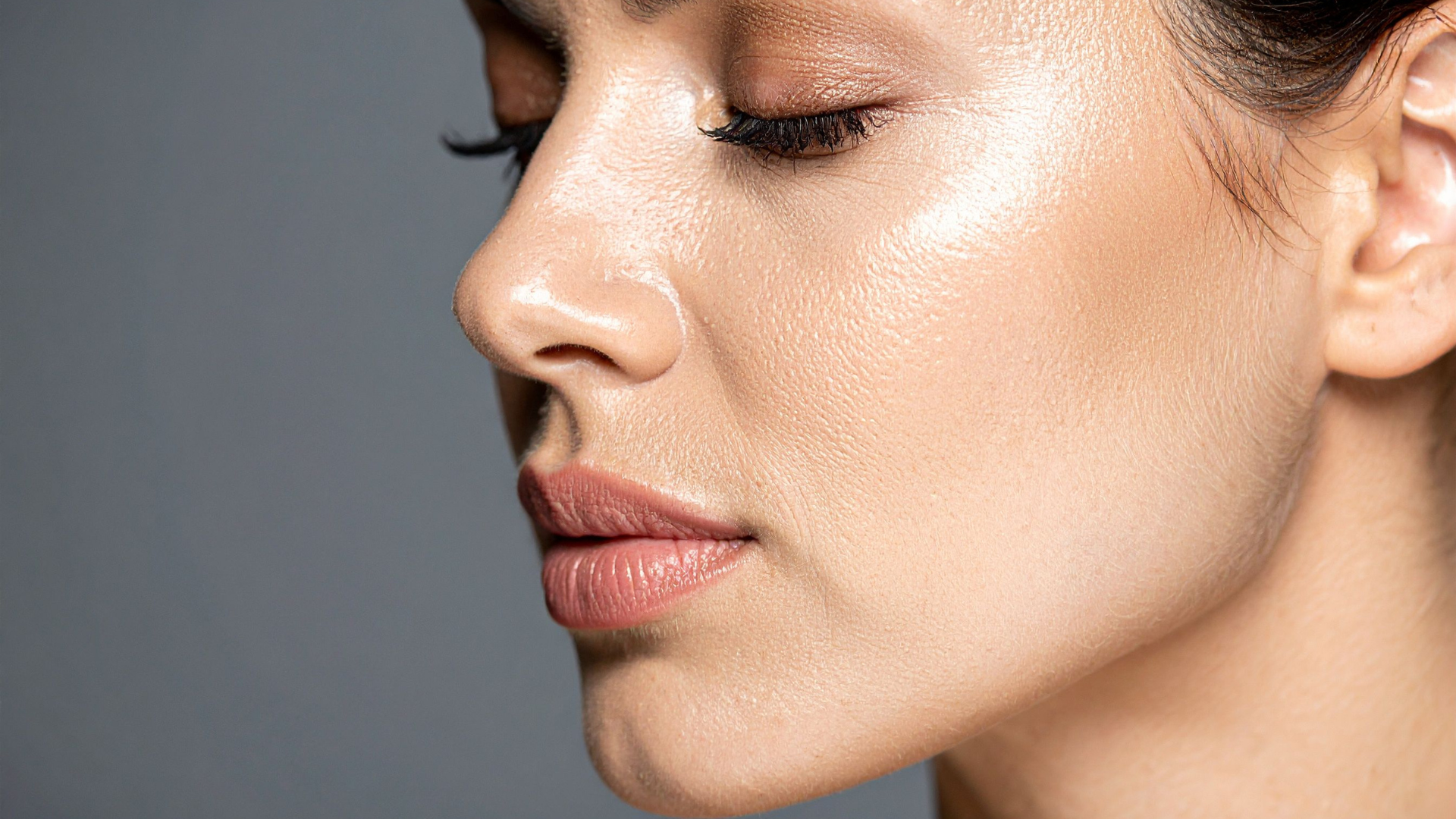 Close-up side profile of a person with closed eyes against a gray background
