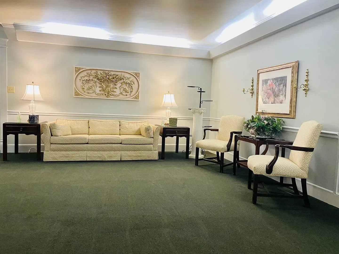 Elegant hotel lobby with cream seating, table lamps, and green carpet walls and framed art