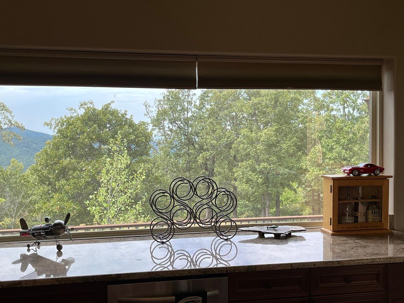 Kitchen countertop with a view of trees through a window. Airplane and metal art displayed.