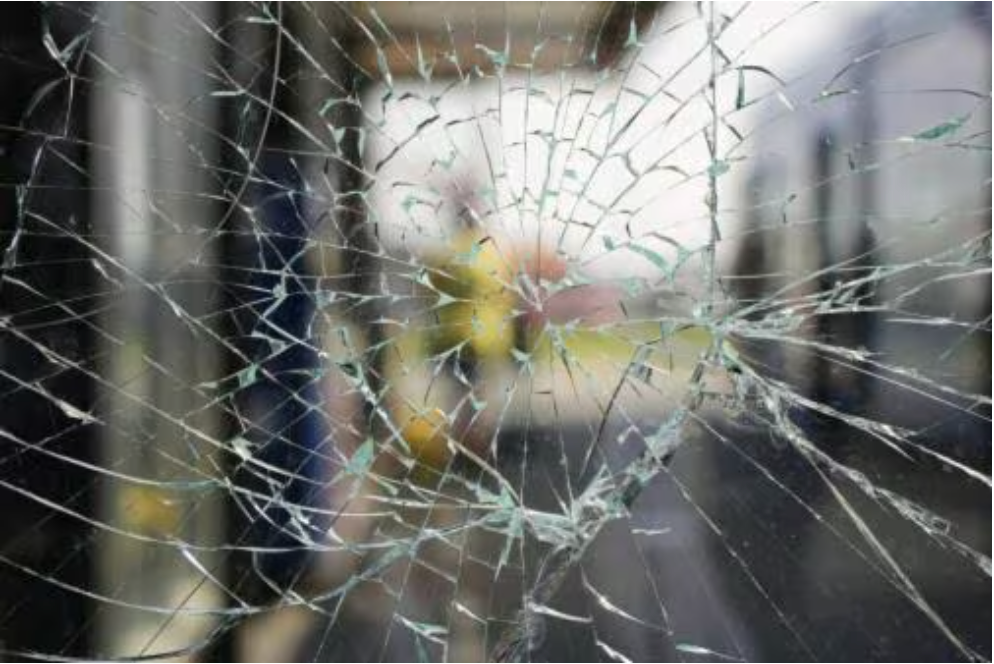Shattered glass window with a blurred view of a train interior and a person.