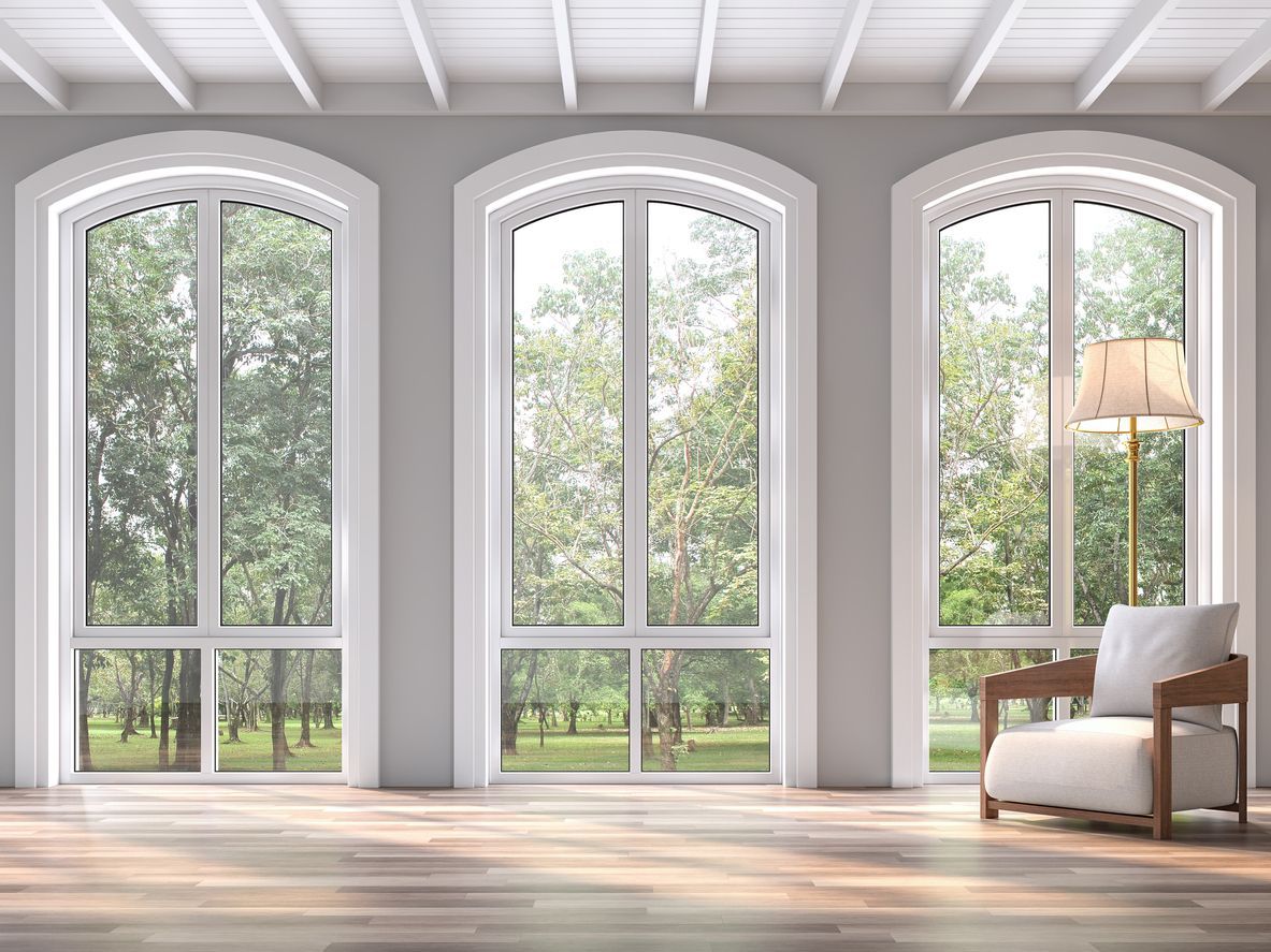 A living room with three arched windows and a chair.
