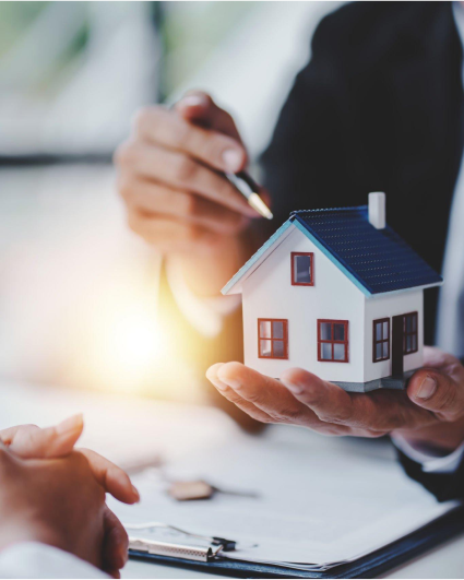 A person is holding a model house in their hands.