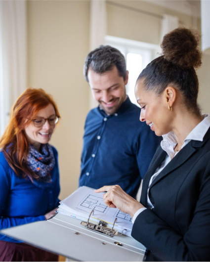 A woman is looking at a binder with a man and woman standing behind her