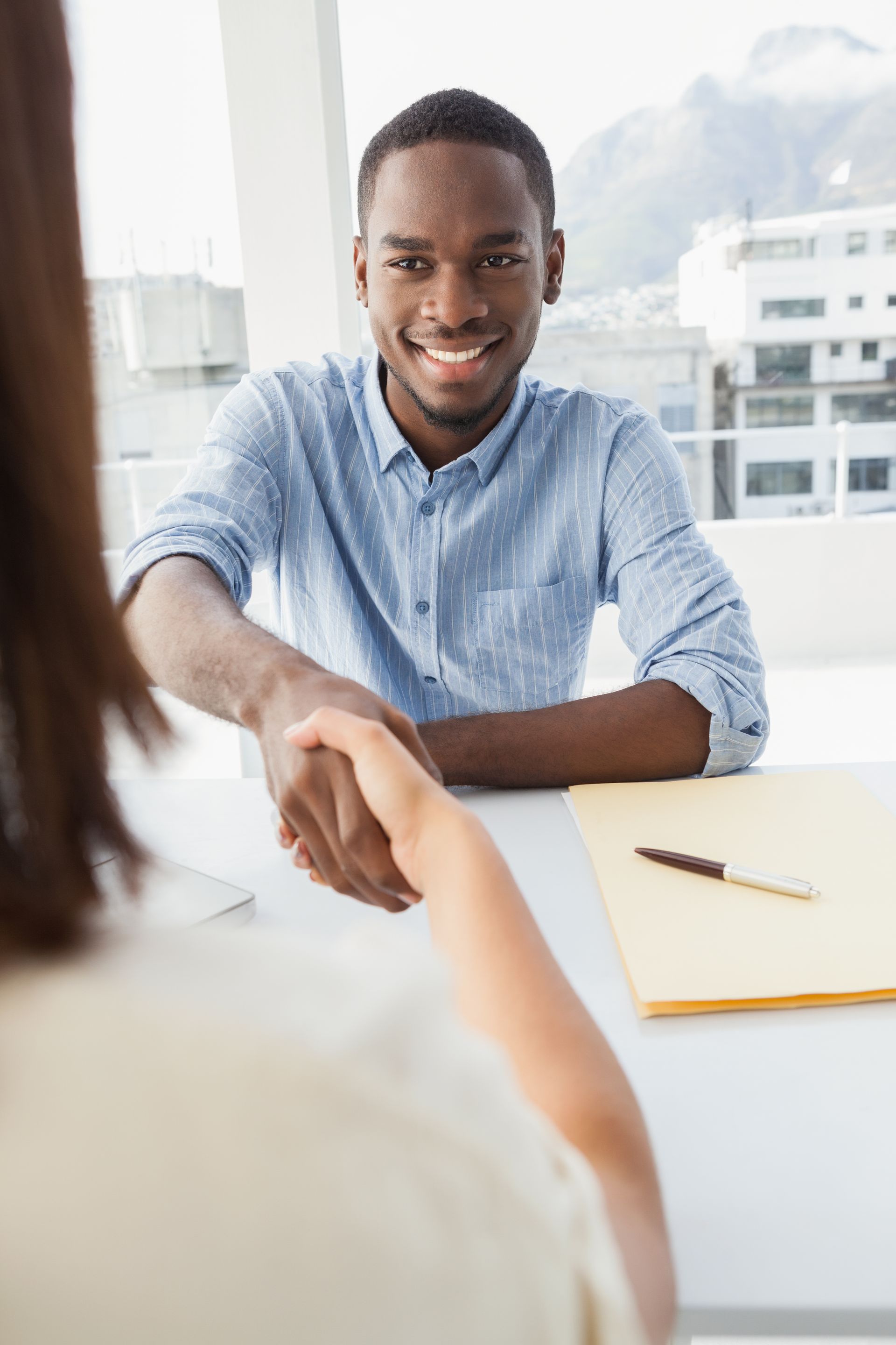 A man is shaking hands with a woman during a job interview.