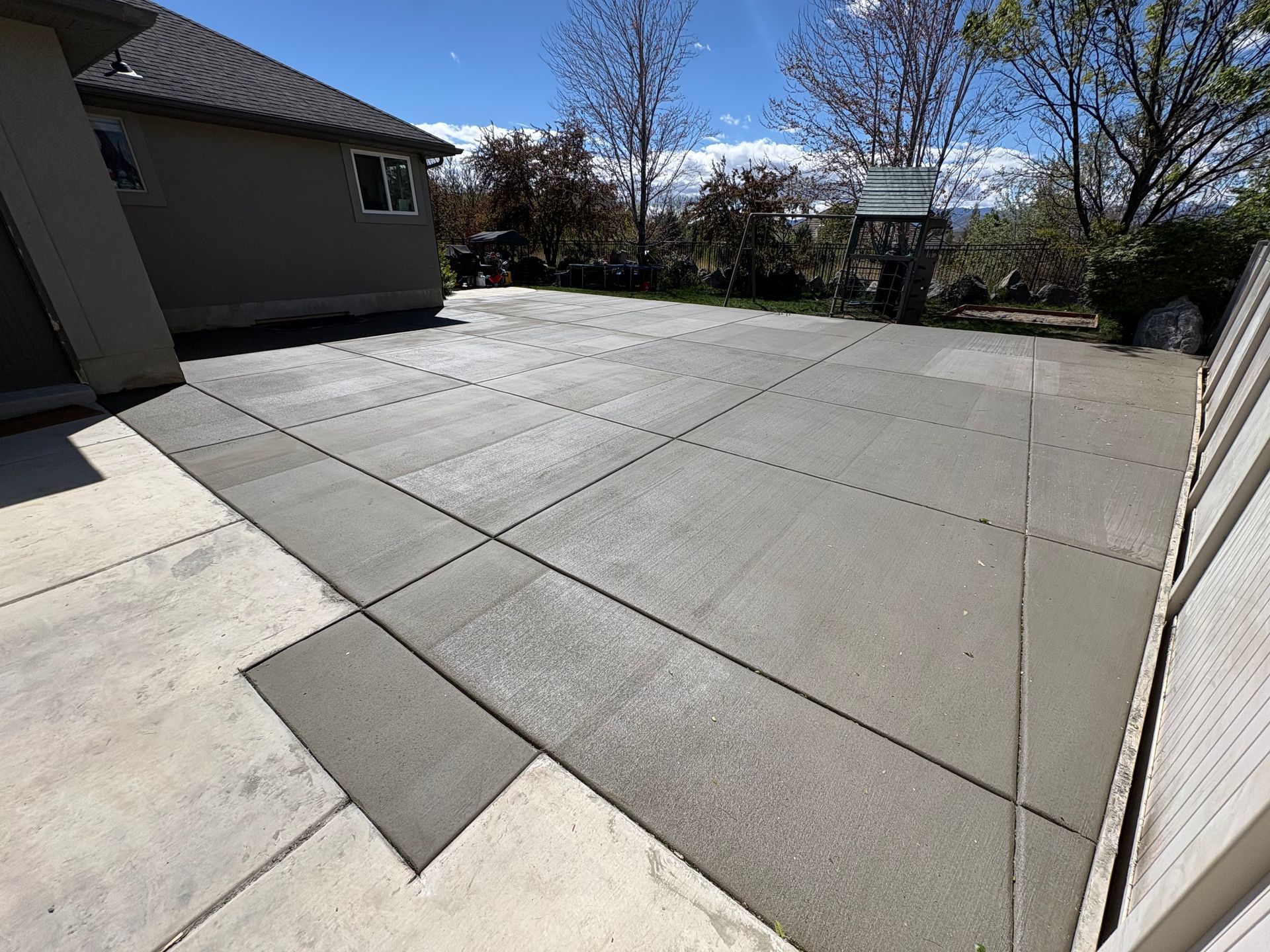 Large concrete patio in the backyard of a single family home.