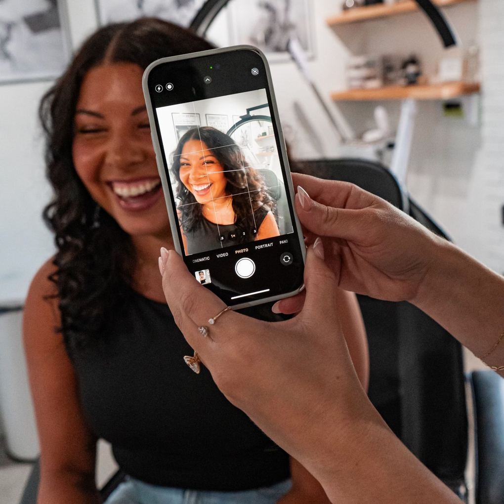 A woman is looking at her face in a mirror.