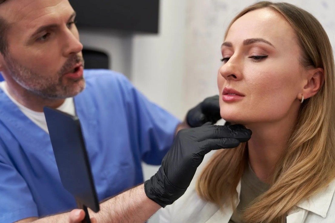 Doctor examining a patient’s face with gloved hands in a clinic setting