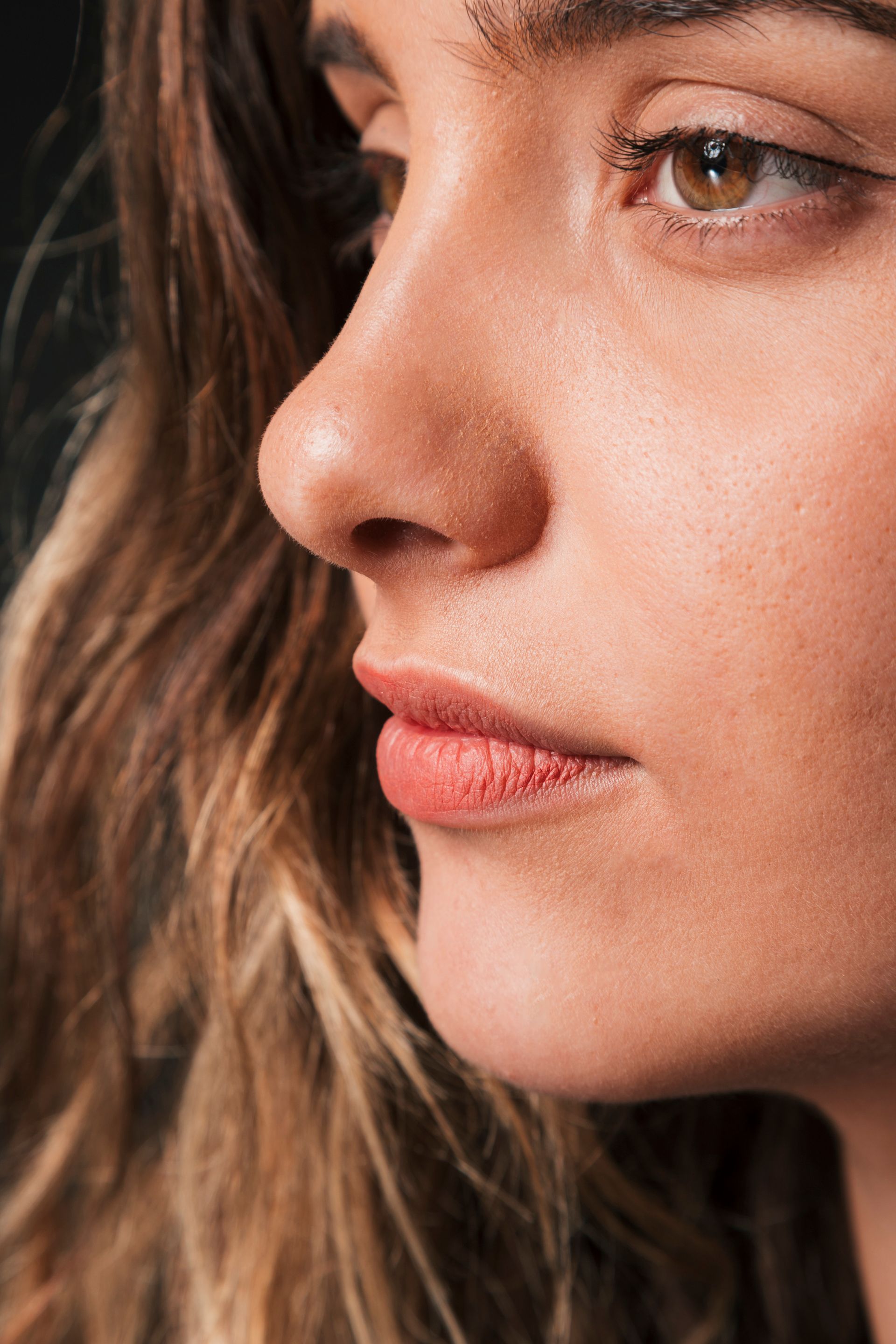A close up of a woman 's face with long hair and red lips.