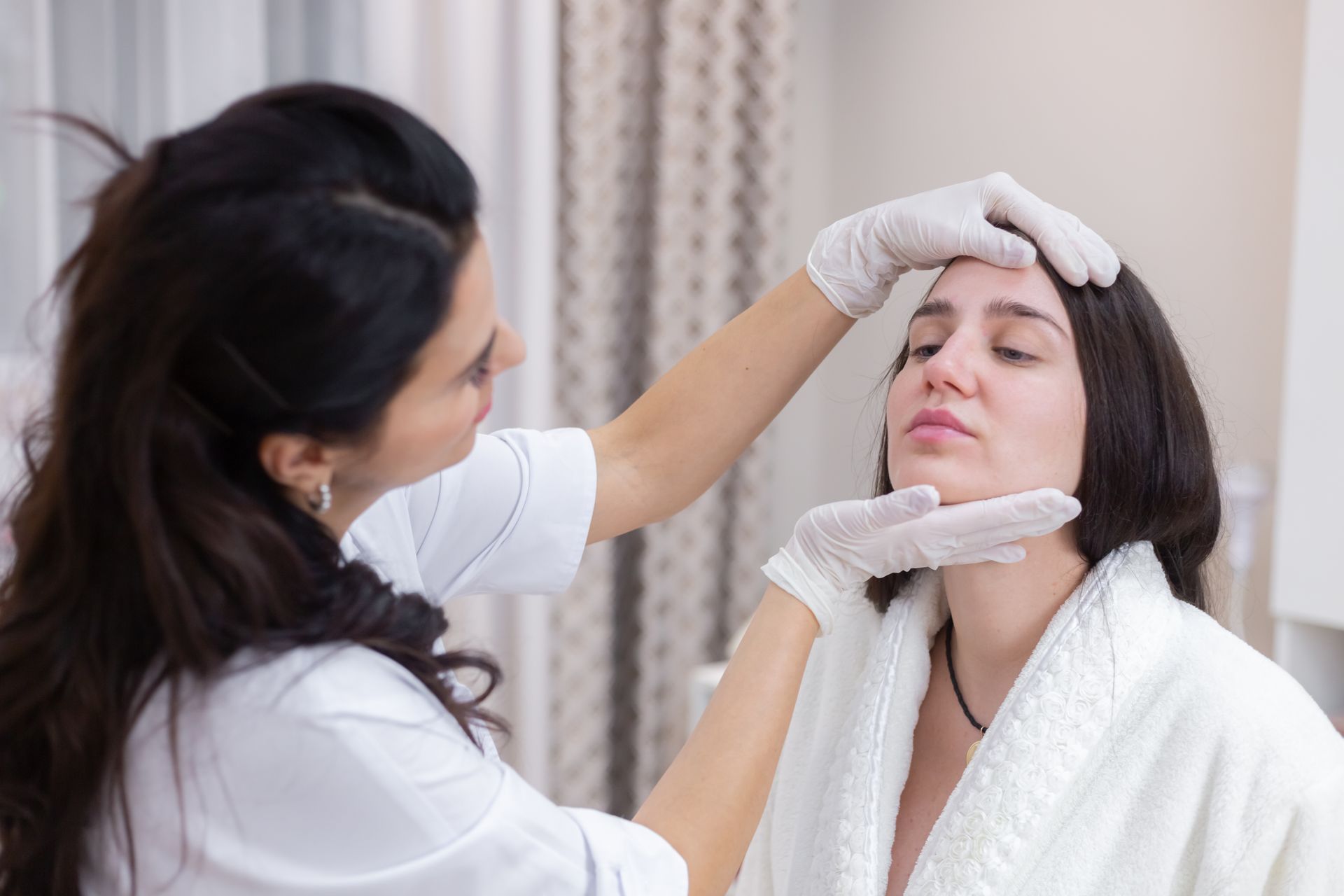 A woman is getting her face examined by a doctor.