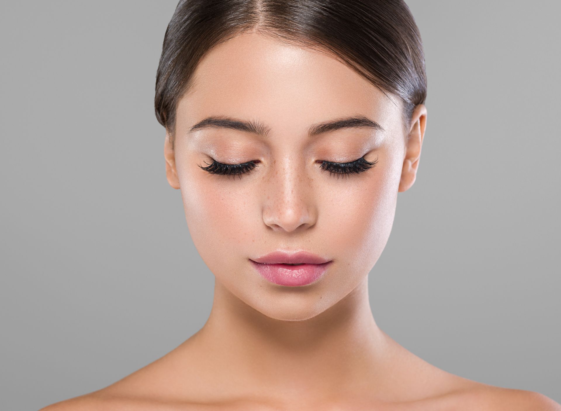 Close-up of a woman with eyes closed against a gray background