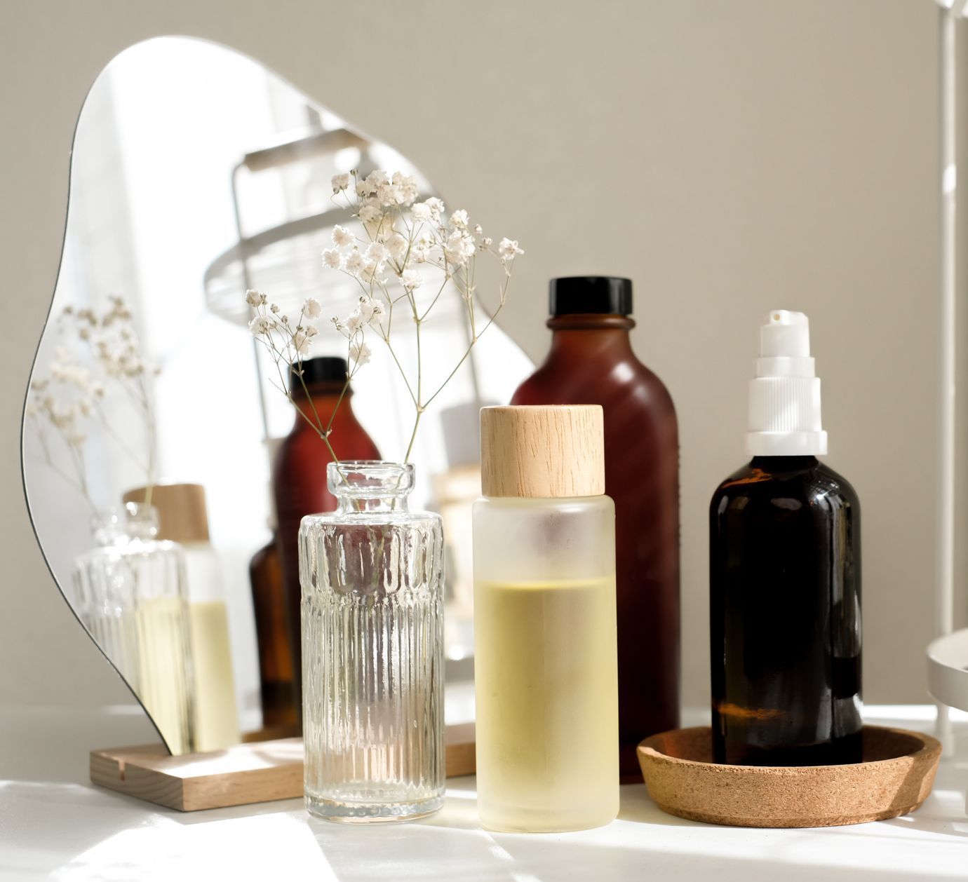 A group of bottles are sitting on a table in front of a mirror.