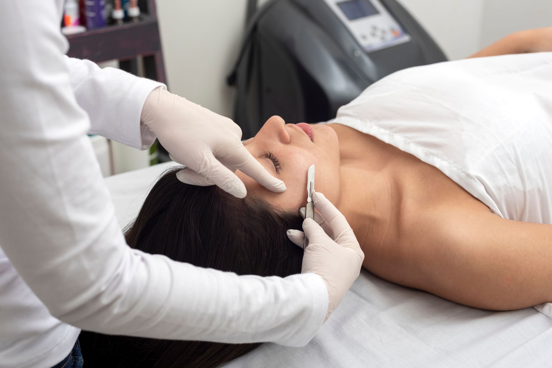 Practitioner performing facial treatment on a reclining client in a spa setting