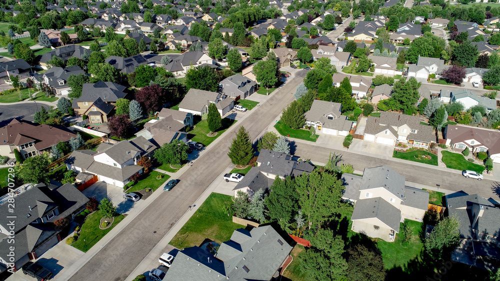 Aerial view of a residential neighborhood with houses, curved roads, and green trees.