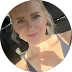 Blond woman in a car, smiling, wearing a tank top. Sunny day.