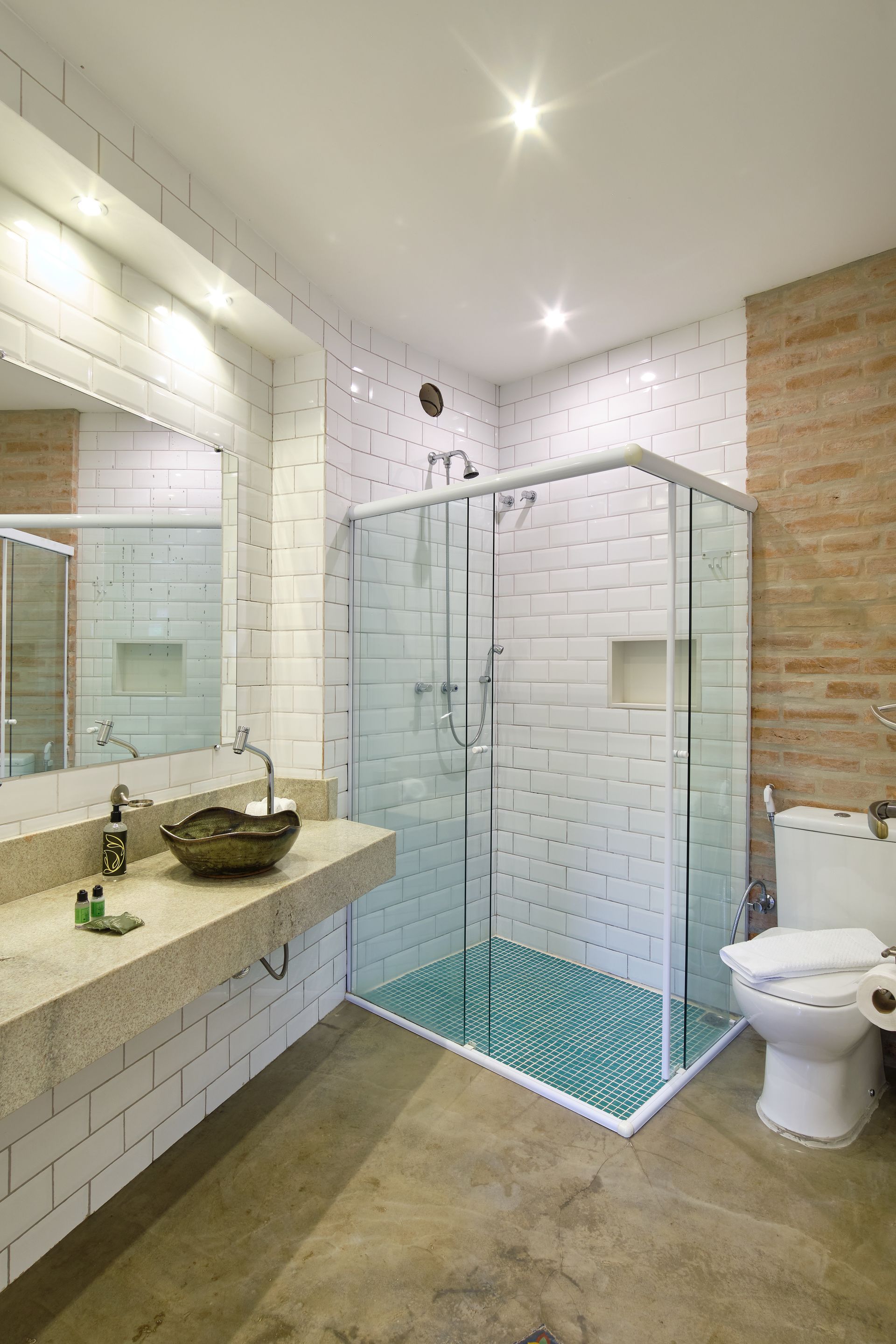 Modern bathroom with glass shower, white tiled walls, vanity sink, and toilet