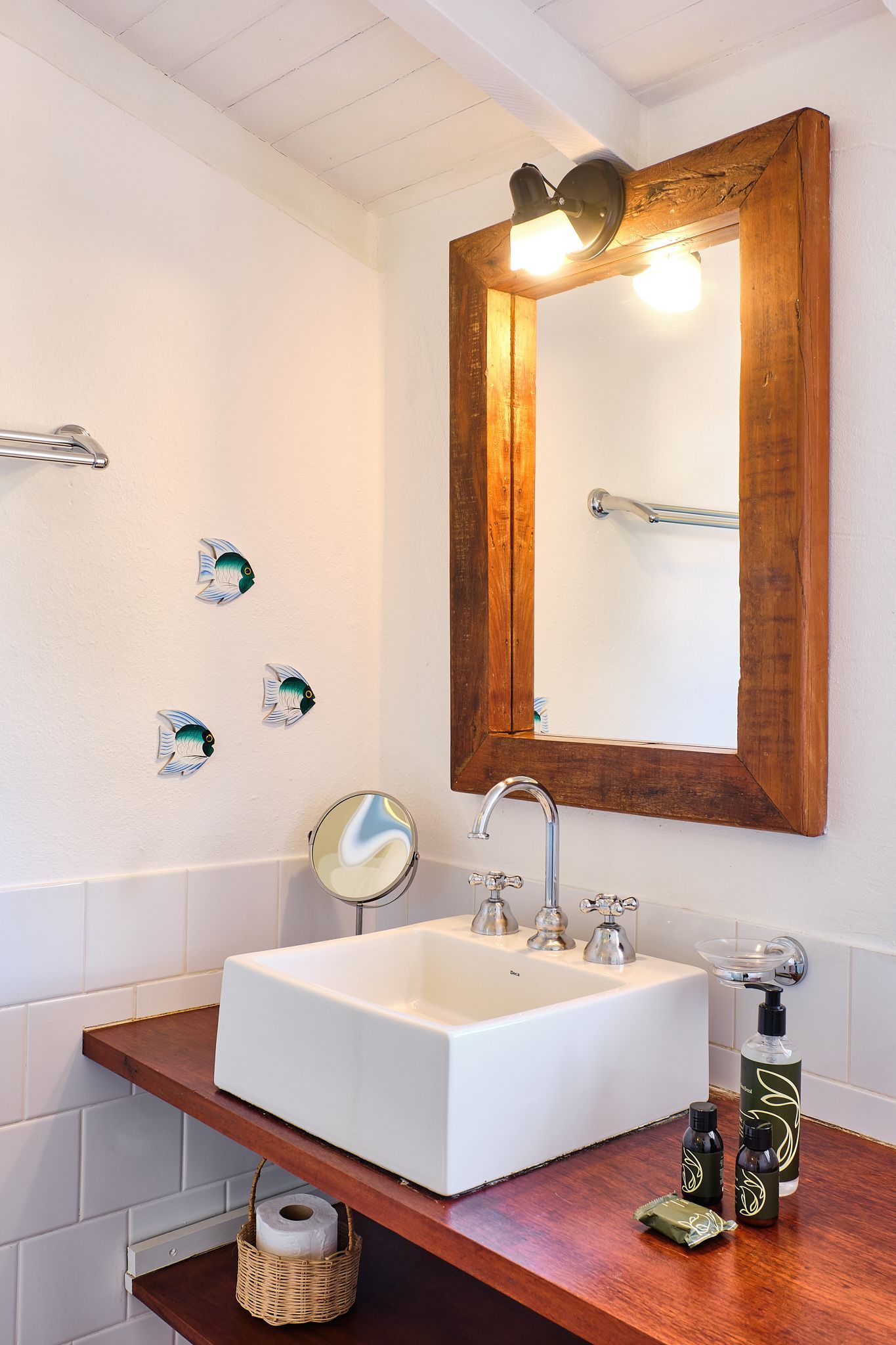 Bathroom vanity with a white square vessel sink on a dark wood counter, mirror, and decorative wall fish ornaments.