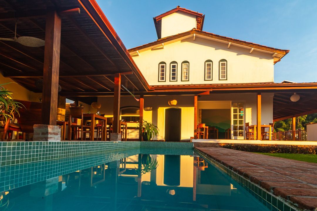 Luxury hotel courtyard with a turquoise pool reflecting a warmly lit building at sunset.