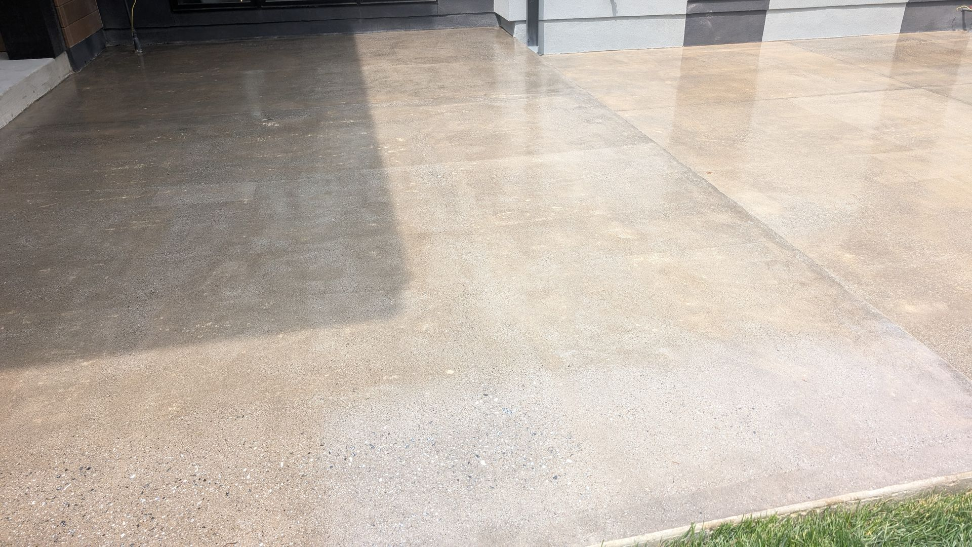 Smooth polished concrete driveway with a light sheen, extending from a modern home's front entry to the lawn edge.