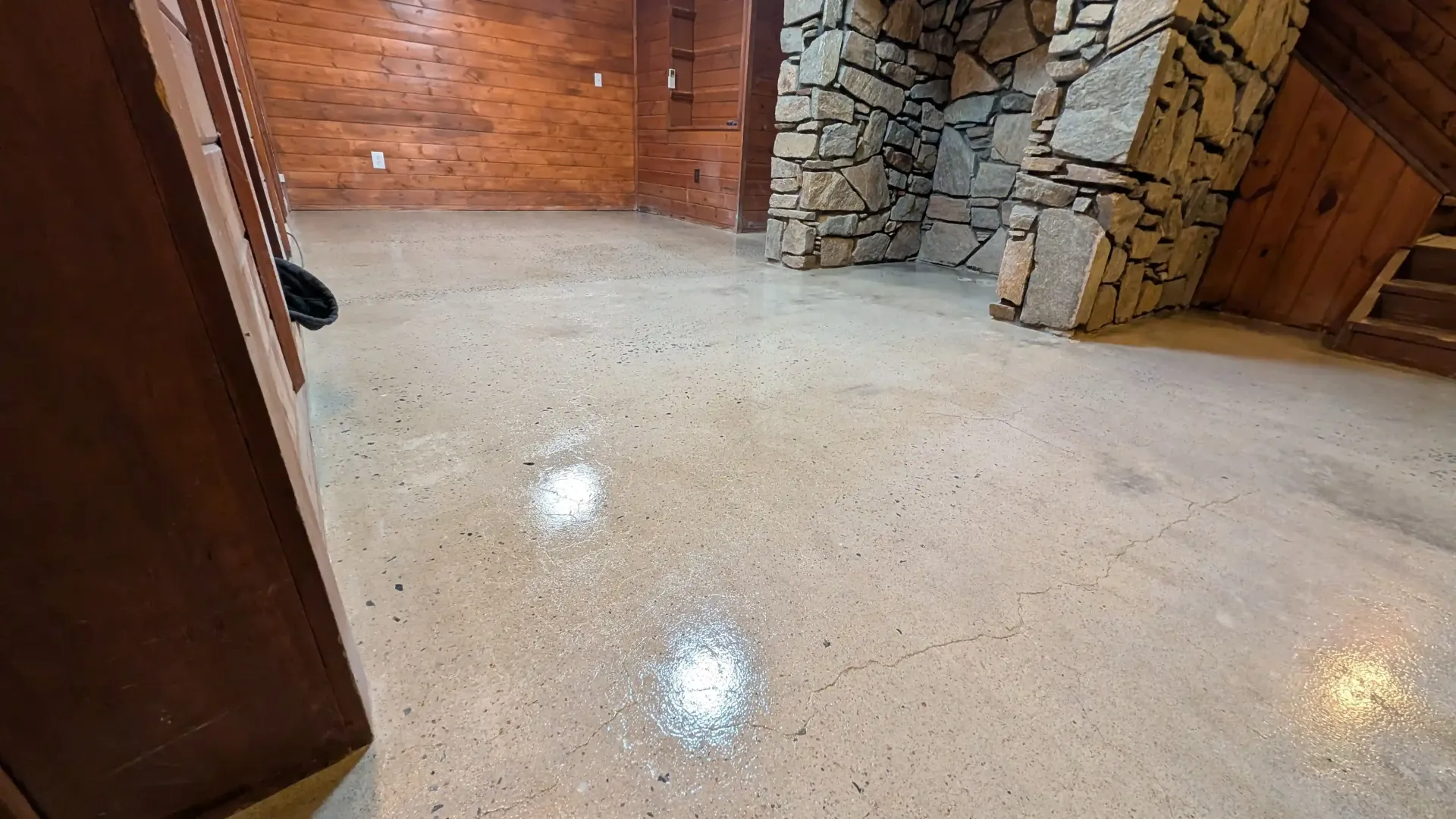 A room with a stone fireplace and a concrete floor.