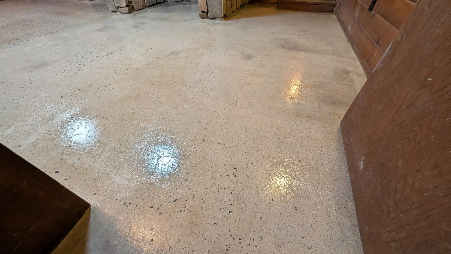 A large room with a stained concrete floor and wooden walls.