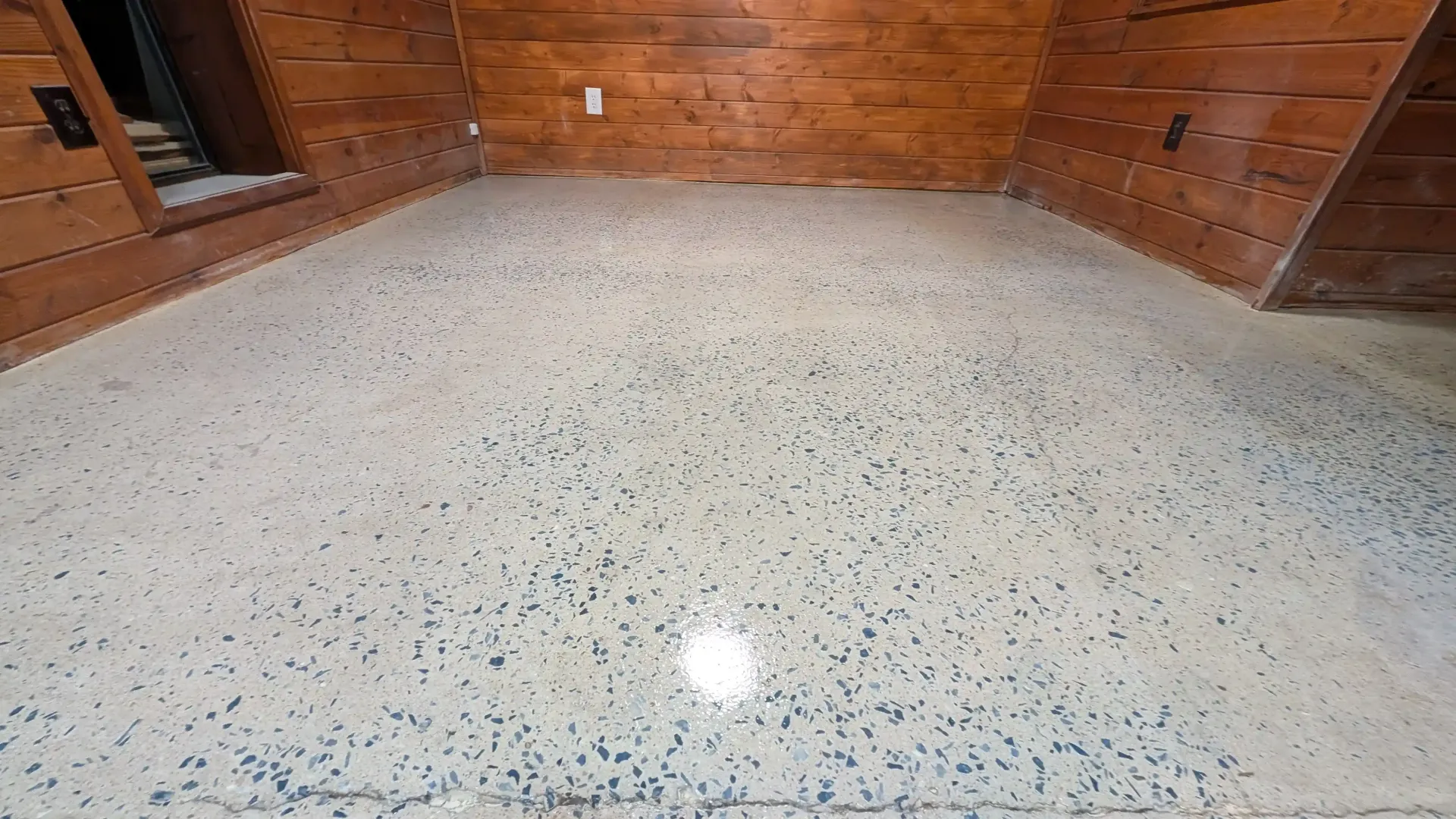 A room with a concrete floor and a wooden wall.